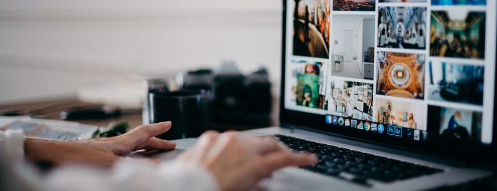 Person typing on a laptop displaying a photo collage on the screen